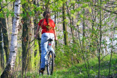 Girl biking in forest clipart