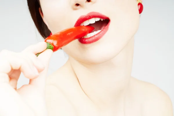 Σέξι γυναίκα που δαγκώνει ένα πιπέρι τσίλι — Φωτογραφία Αρχείου