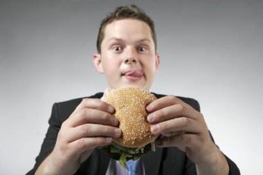 Hungry businessman holding a burger clipart