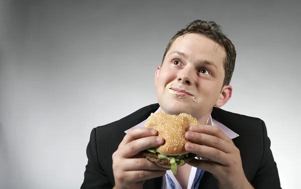 Ung affärsman njuter en hamburge — Stockfoto