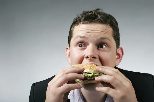 大きなハンバーガーを楽しんでいる空腹の実業家 — ストック写真
