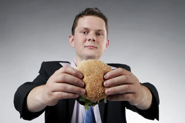 Uomo d'affari che tiene un hamburger Foto Stock