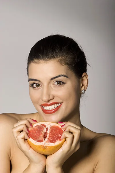 Улыбающаяся женщина с кусочком грейпфрута — стоковое фото