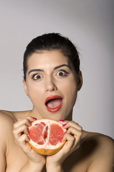Šokovaná žena s plátkem grapefruitu — Stock fotografie