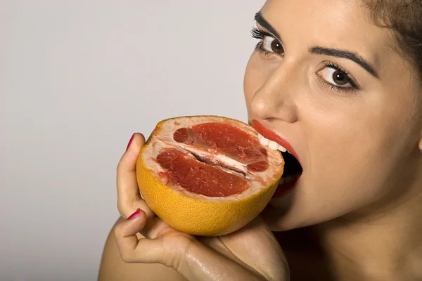 Сексуальная женщина, кусающая грейпфрутовый ломтик — стоковое фото
