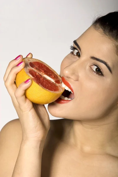 Sexy woman biting a grapefruit slice — Stock Photo, Image