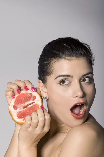 Šokovaná žena s plátkem grapefruitu — Stock fotografie