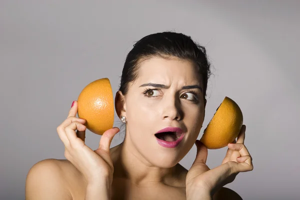 Geschockte Frau mit Grapefruitscheibe Stockbild
