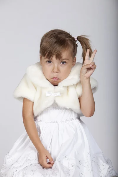 Sehr lustiges Bild eines schüchternen kleinen Mädchens, das zwei Finger in die Höhe streckt — Stockfoto