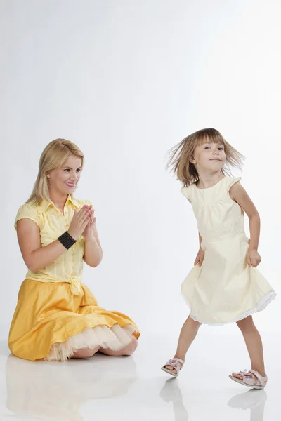 Молодая мама аплодирует своей маленькой дочери, танцующей — стоковое фото