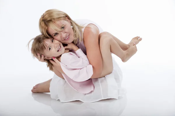Jovem bela mãe segurando sua filha em um abraço amoroso — Fotografia de Stock