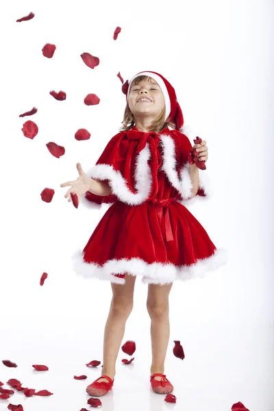 Glückliches kleines Weihnachtsmädchen und fliegende Rosenblätter — Stockfoto