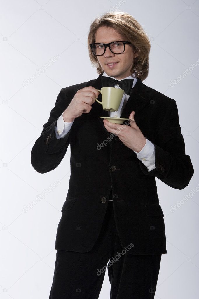 Rich young gentleman is drinking a cup of tea or cafee
