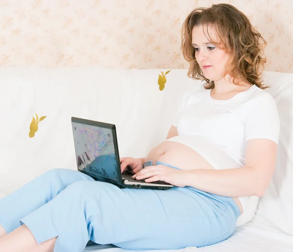 Den gravida kvinnan med den bärbara datorn och en mobiltelefon — Stockfoto