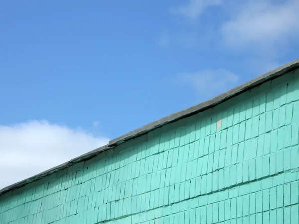 Green brick wall on blue sky, clouds — Stok fotoğraf