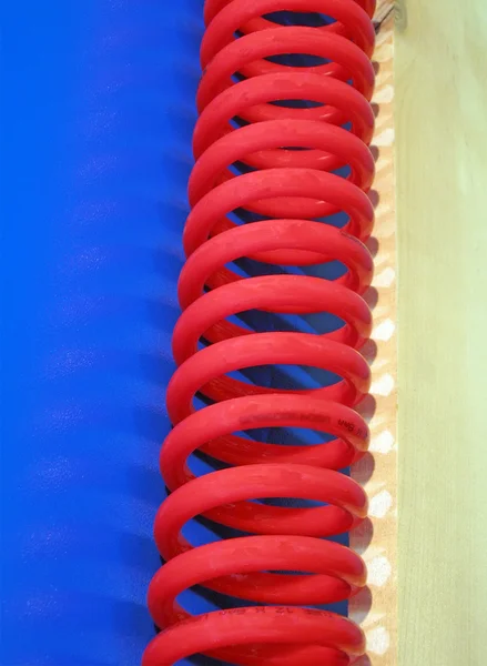 Cabo curvo vermelho, superfície azul — Fotografia de Stock