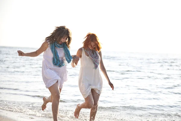 Dos hermosas chicas corriendo en la playa . — Foto de Stock