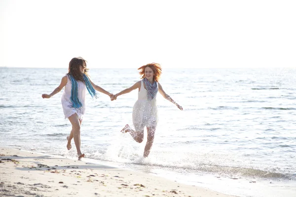 Dos hermosas chicas corriendo en la playa . — Foto de Stock
