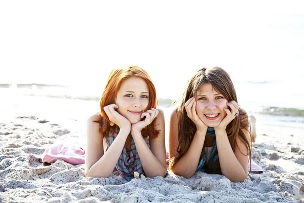 Two beautiful girls lie on the beach. — Stock Photo, Image