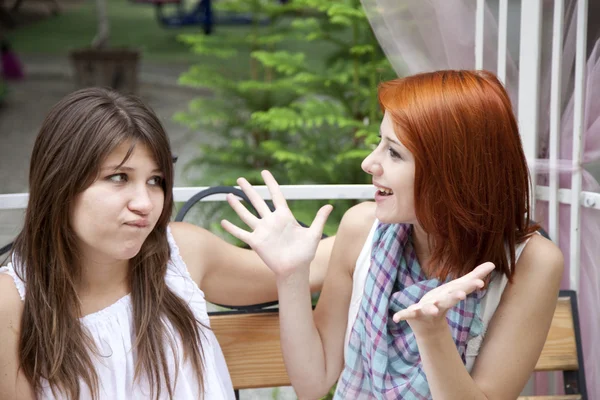 两个女孩在花园长凳上说长道短. — 图库照片