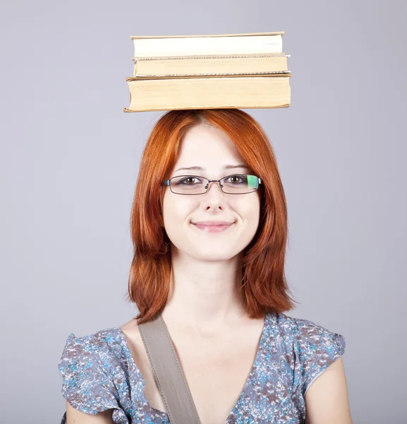 Une rousse tient des livres sur sa tête. Plan studio . — Photo