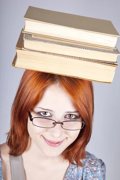Rudowłosa dziewczyna prowadzenia ksiąg na głowie. łapka. — Zdjęcie stockowe