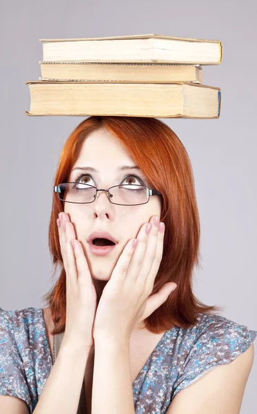 Рудоволоса дівчина тримає книжки на голові. Студійний знімок . — стокове фото
