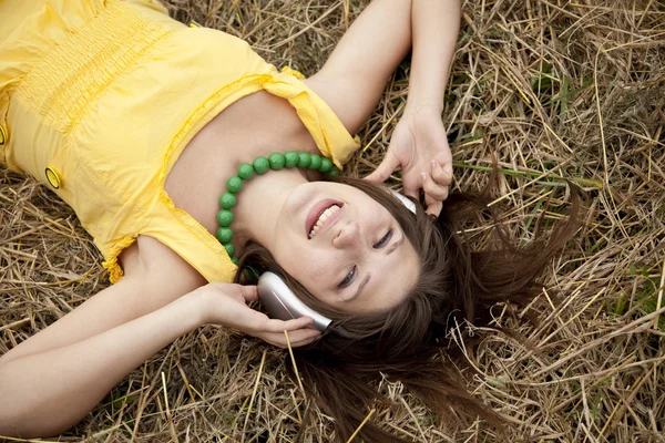 Joven hermosa chica en amarillo con auriculares en el campo . —  Fotos de Stock