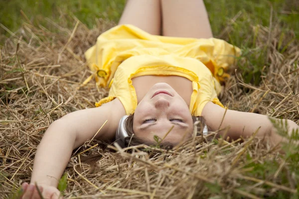 Young beautiful girl in yellow with headphones at field. — Stock Photo, Image