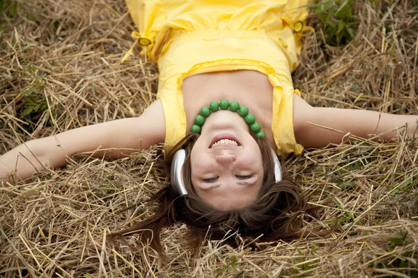 Όμορφη κοπέλα με το κίτρινο με ακουστικά στο πεδίο. — Φωτογραφία Αρχείου