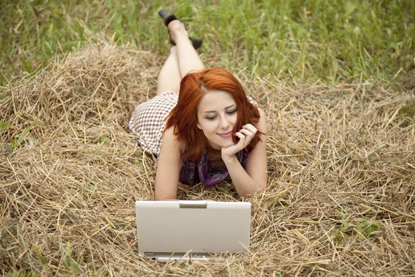 Jonge mode meisje met laptop liggen op veld — Stockfoto