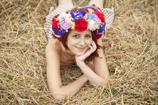 Menina em grinalda nacional eslavo deitado no campo . — Fotografia de Stock