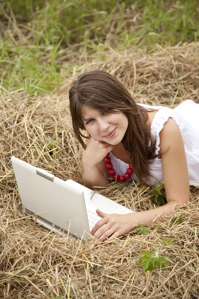 Menina de moda jovem com notebook deitado no campo — Fotografia de Stock