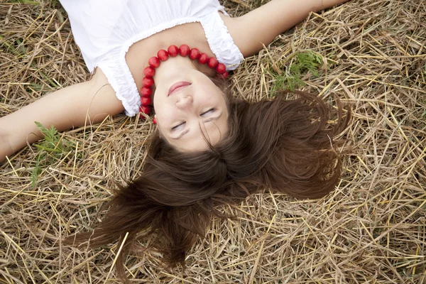 Beautiful girl lying at hay field. — Stock Photo, Image