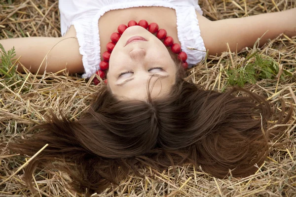 Menina bonita deitada no campo de feno . — Fotografia de Stock