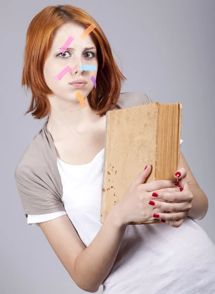 Рыжеволосый студент с книгой и заметками на лице . — стоковое фото