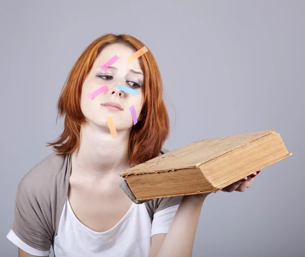 Roodharige student met boek en notities op gezicht. — Stockfoto