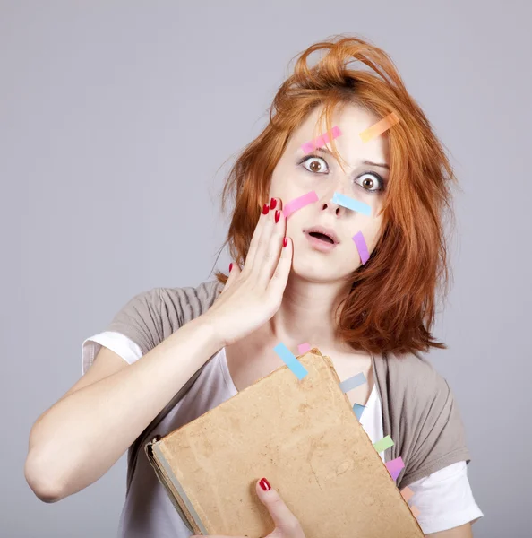 Red-haired student with book and notes on face. — Stock Photo, Image