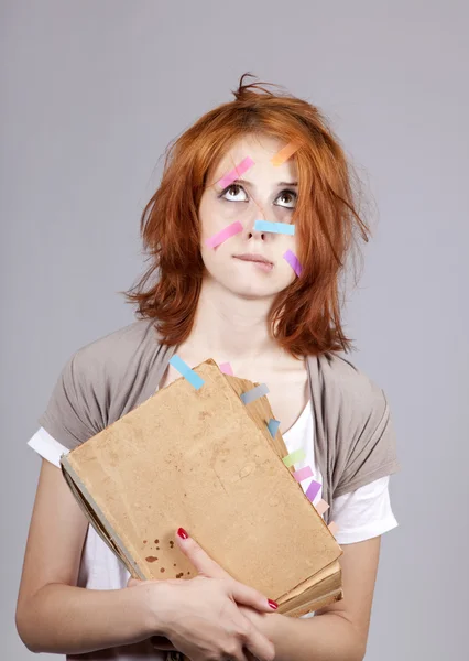 Rödhårig student med bok och anteckningar på ansikte. — Stockfoto