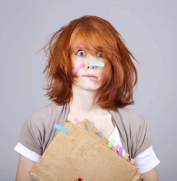 Estudante de cabelos vermelhos com livro e notas no rosto . — Fotografia de Stock