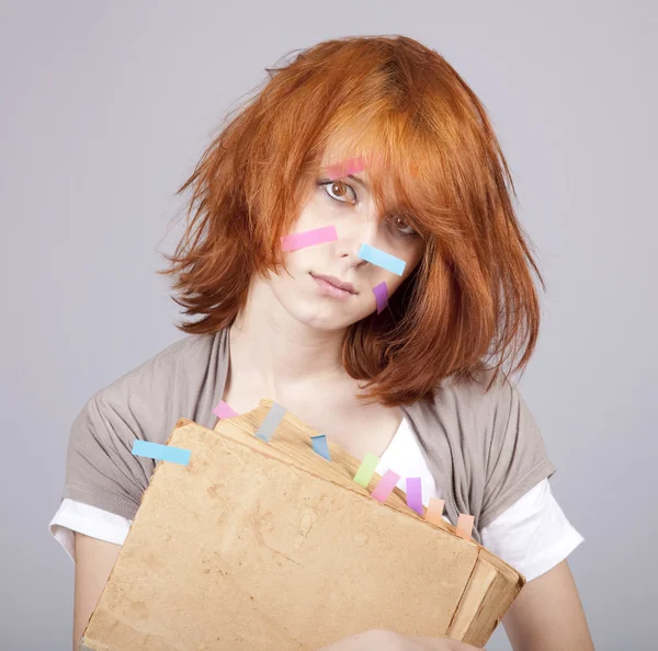 Estudante de cabelos vermelhos com livro e notas no rosto . — Fotografia de Stock