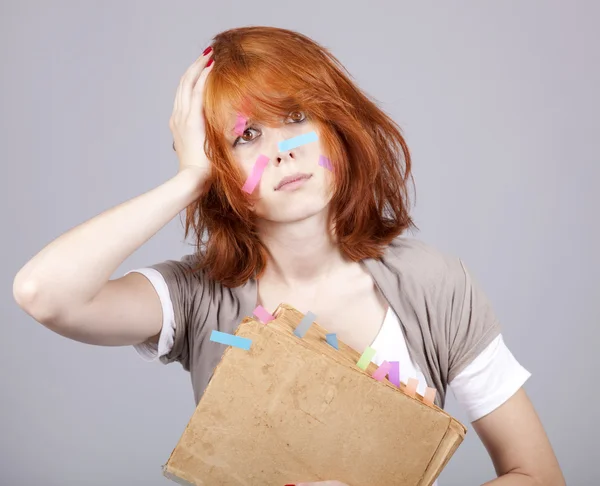 Red-haired student with book and notes on face. — Stock Photo, Image