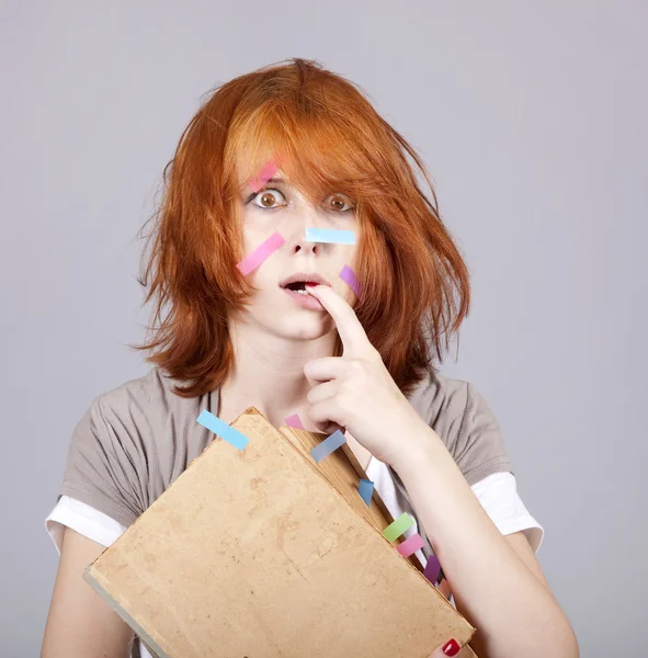Rudowłosa studenta z książki i notatki na twarz. — Zdjęcie stockowe