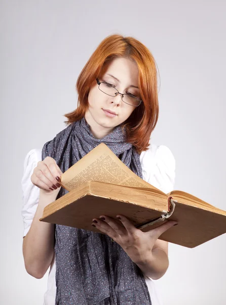 Молодая сомневающаяся девушка в очках со старой книгой — стоковое фото