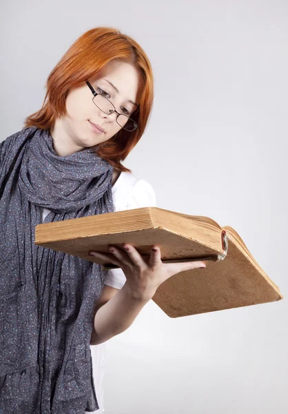 Молодая сомневающаяся девушка в очках со старой книгой — стоковое фото
