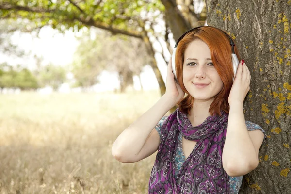 Молода усміхнена мода з навушниками біля дерева . — стокове фото