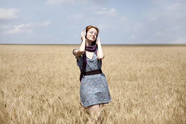 Jonge lachende mode meisje met hoofdtelefoon aan het tarweveld. — Stockfoto