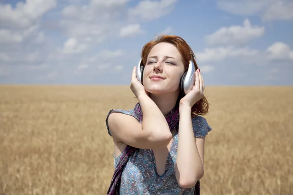 Jeune mode souriante avec écouteurs au champ de blé . — Photo