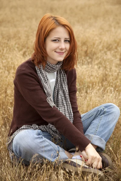 Bella ragazza dai capelli rossi seduto a giallo erba autunno . — Foto Stock