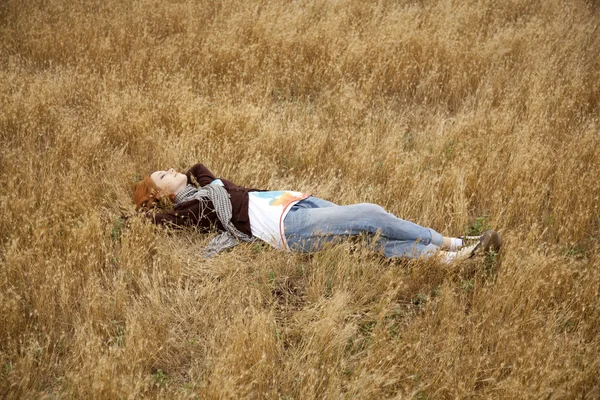 年轻漂亮的女孩躺在黄色的秋天字段. — 图库照片